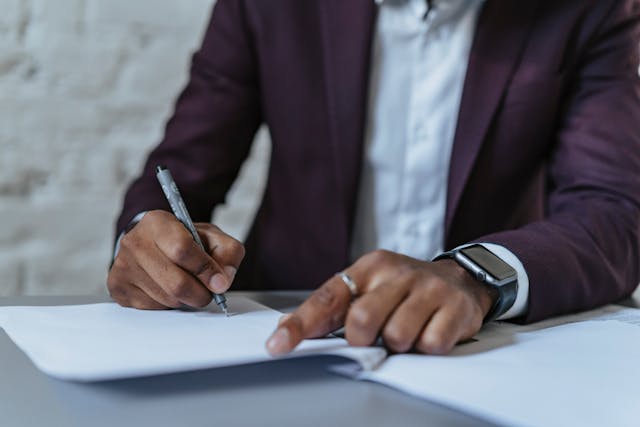 a person in a dark suit signing a document